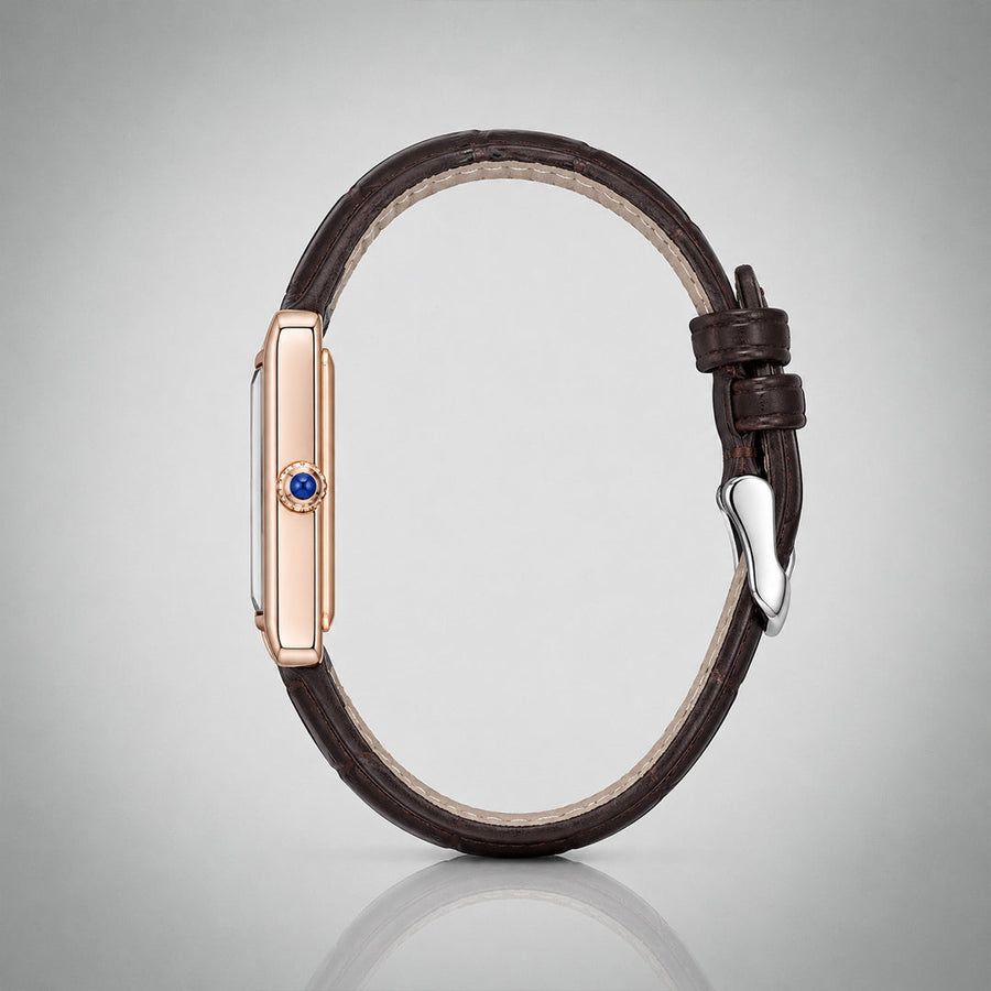 Side profile of the 1927 gold tank case with blue cabochon crown and brown leather strap — architectural view